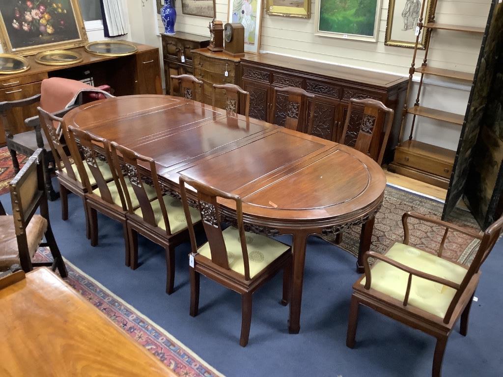 A 20th century Chinese carved hardwood dining room suite comprising sideboard fitted with four drawers above four carved panelled cupboard doors, shelved interior, raised on bracket base, length 183cm, depth 48cm height